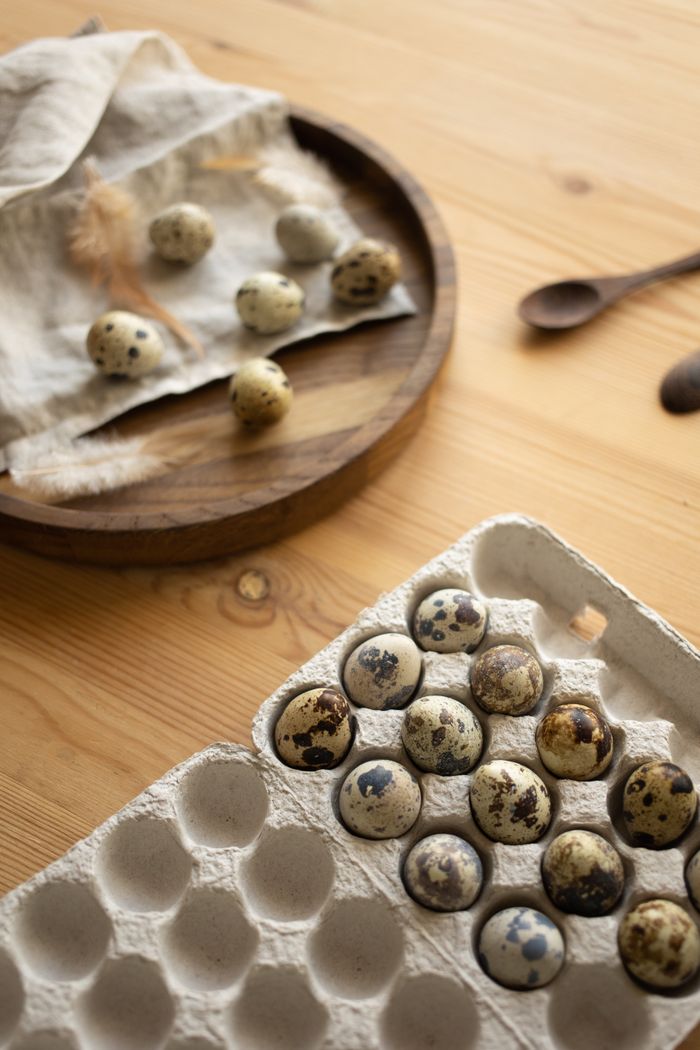 Crafting Captivating Headlines: Your awesome post title goes here A selection of quail eggs displayed on a wooden surface with a carton and round tray.